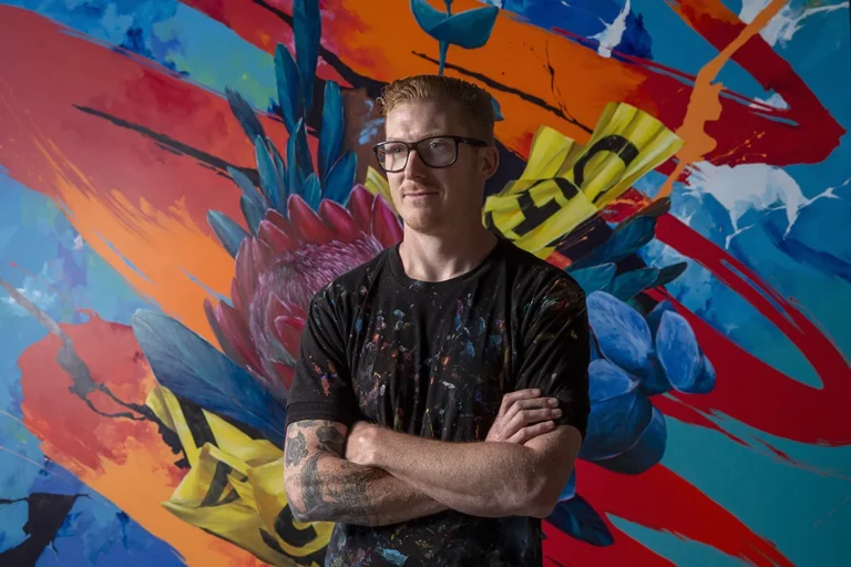 Artist MEGGS in front of artwork